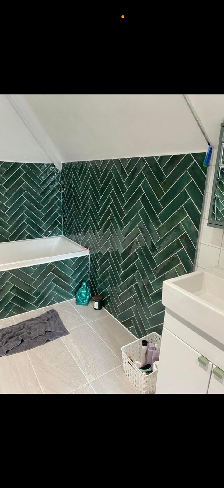 Green herringbone tiled bathroom